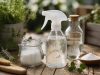 Désherbant naturel bicarbonate et vinaigre : dosages et recettes Spray de désherbant naturel maison posé sur une allée dallée envahie de mauvaises herbes, à côté d'un flacon de vinaigre blanc et d'un pot de bicarbonate de soude